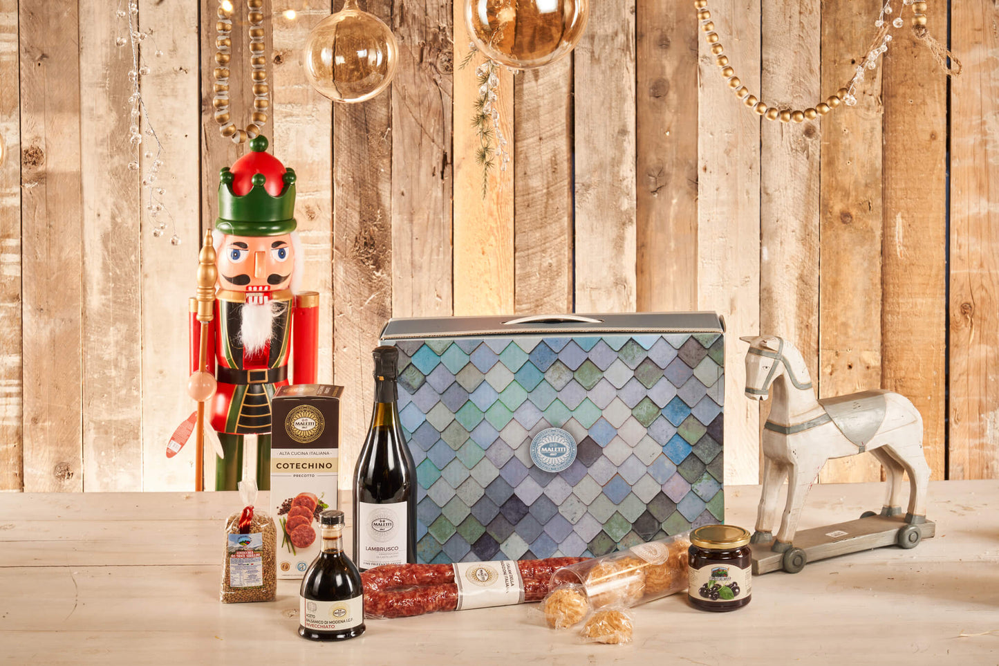 Dono di natale di vizioDiVino chiamato lo "Lo schiaccianoci a Modena". All'interno contiene: aceto balsamico di Modena IGP invecchiato 250 ml; cotechino precotto Maletti 500 g; lenticchie dei Monti Sibillini 250 g; amaretti morbidi modenesi 200 g; confettura di amarene 350 g; salsiccella emiliana s.v. 450g; lambrusco grasparossa di Castelvetro DOC 75 cl..