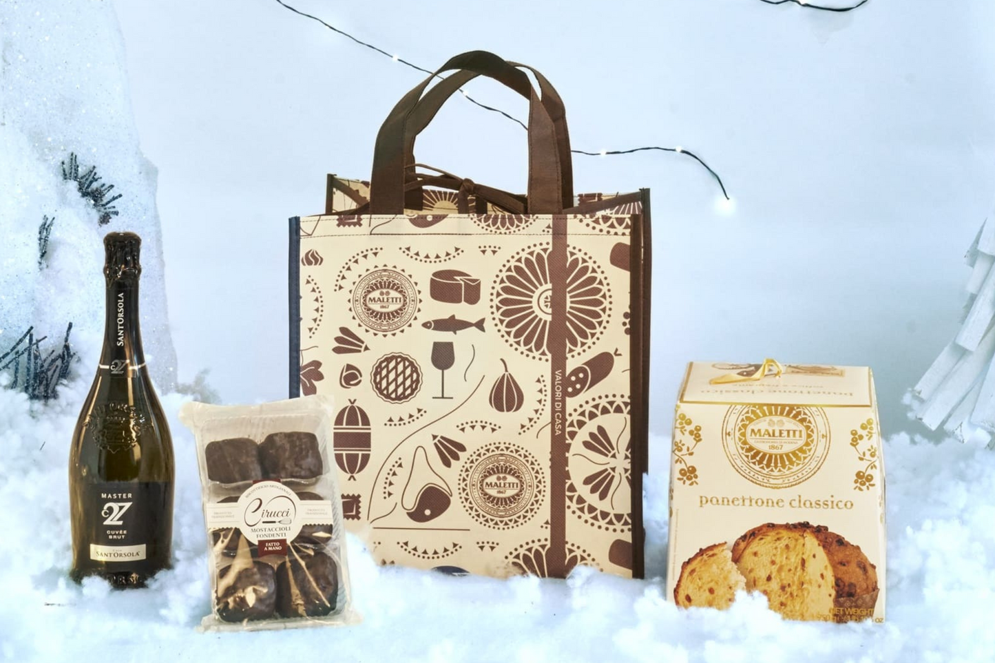 Cesta Natalizia Enogastronomica "Ametista" con Panettone classico, Mostaccioli fondenti, Spumante Cuveé Brut e shopper natalizia, confezionata in una elegante borsa regalo.