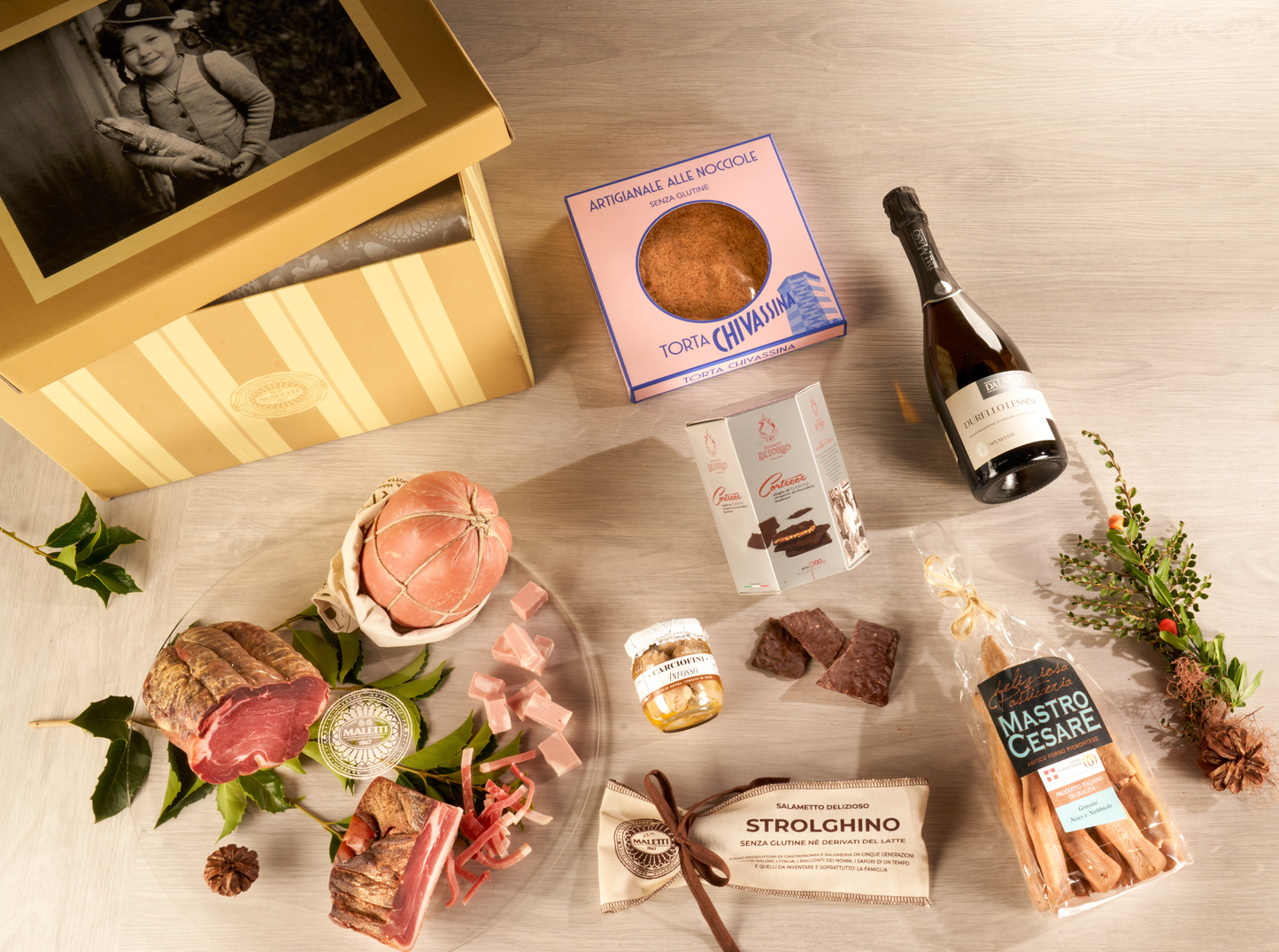 Cesta natalizia enogastronomica "Il Natale del Norcino" con salumi artigianali, mortadella, fiocco di prosciutto, speck, grissini gourmet, carciofini, dolci tipici e spumante in elegante scatola regalo.