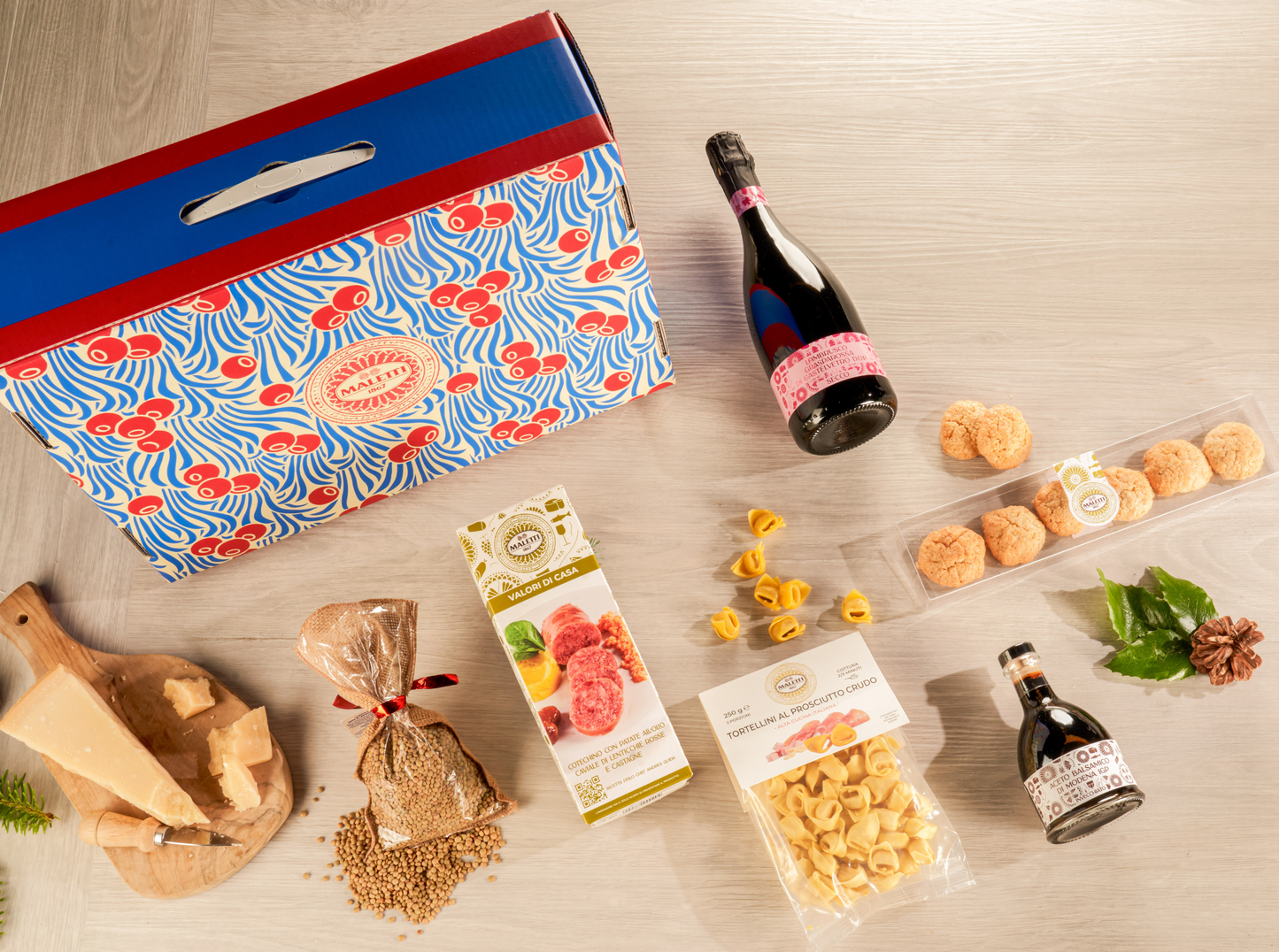 Cesta natalizia enogastronomica "Un Natale a Modena" con tortellini freschi, cotechino, lenticchie, Parmigiano Reggiano DOP, aceto balsamico IGP, amaretti modenesi, Lambrusco Grasparossa e valigetta regalo elegante.