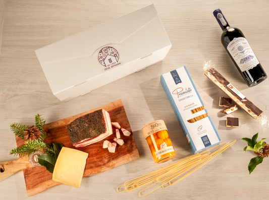 Cesta natalizia enogastronomica "Un Natale in Casa" con guanciale del norcino, pecorino di Amatrice, spaghettoni, datterino giallo biologico, Merlot Rubicone, cioccolato bianco e cofanetto regalo artigianale.