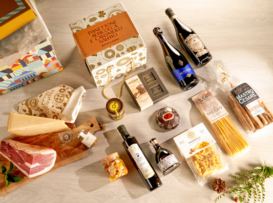 Cesta natalizia enogastronomica di lusso "Un Natale Lussuoso" con panettone artigianale, Amarone, Franciacorta, prosciutto San Daniele, Parmigiano 26 mesi e specialità gourmet italiane in elegante scatola regalo.