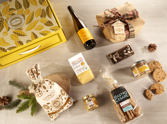 Cesta natalizia enogastronomica "Un Natale Gourmet in Montagna" con stinco, polenta, funghi porcini, panettone, Gewürztraminer e biscotti, confezionata in valigetta elegante.